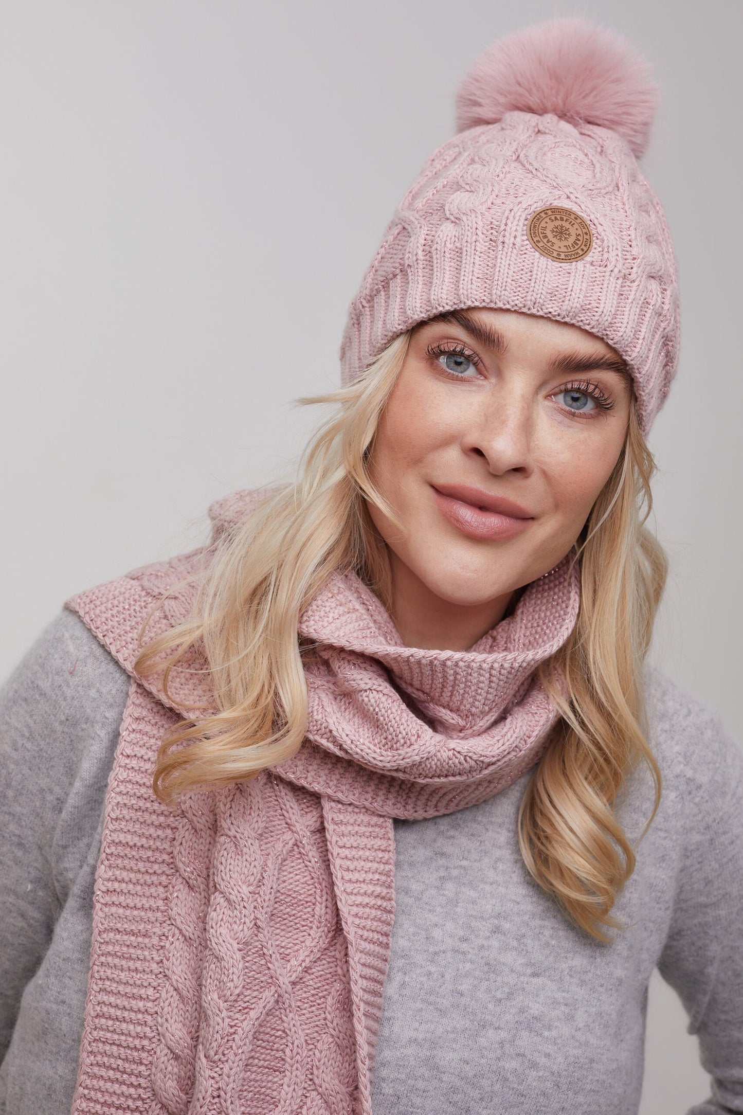 Ženska pletena zimska kapa Scarlett s cofom, pudrasto roza s svetlečo nitko | Shopacita