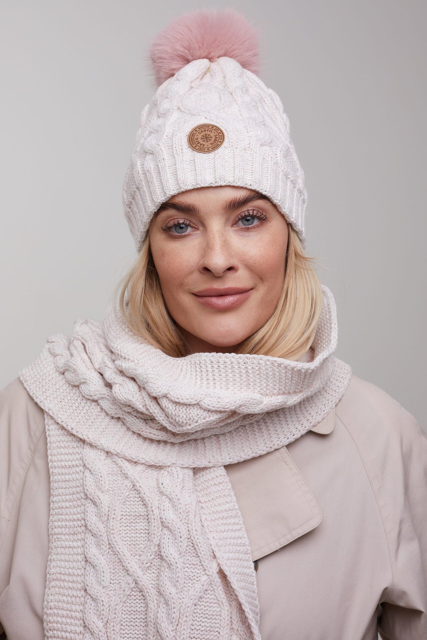 Ženska pletena zimska kapa Scarlett s cofom, smetanovo roza s svetlečo nitko | Shopacita